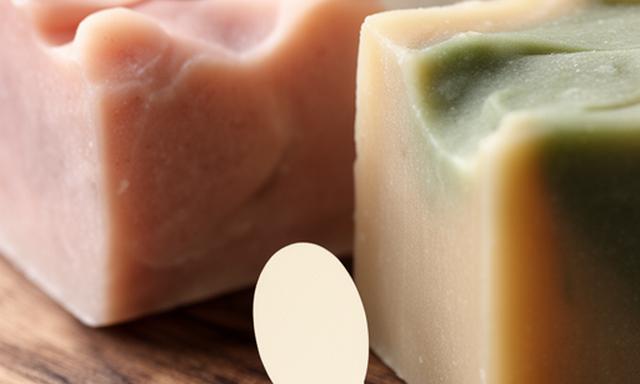 Primer plano de jabones artesanales con texturas naturales y tonos suaves sobre una superficie de madera